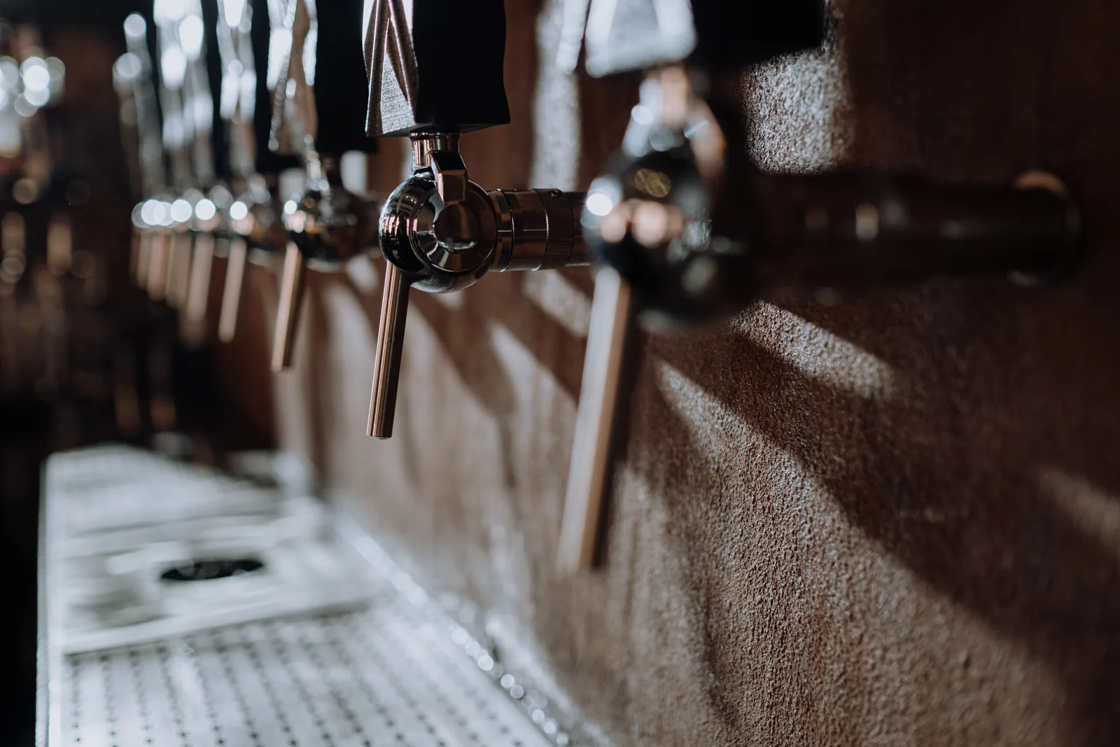 A row of beer taps along a brewery bar