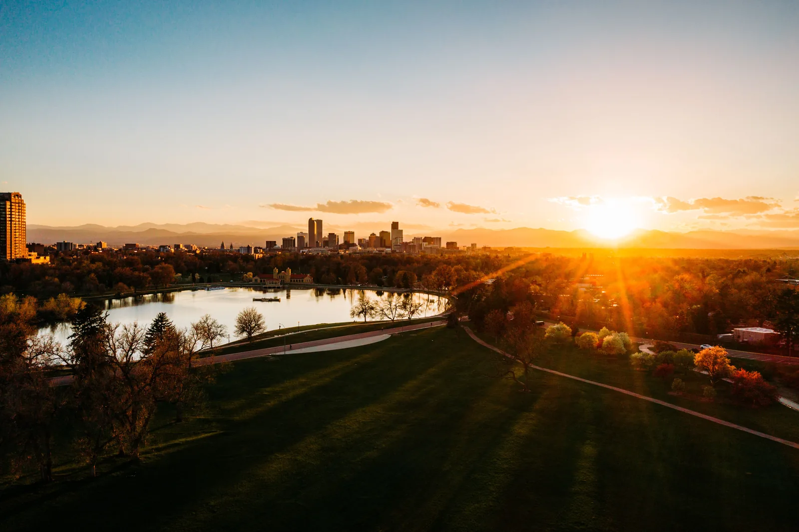 The Denver skyline at sunset seen across a park lake