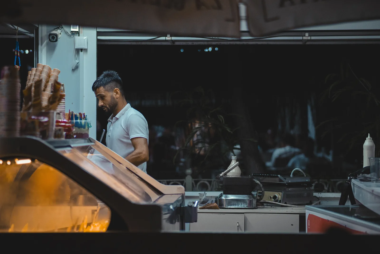 A worker scooping cones behind the counter of an ice cream shop