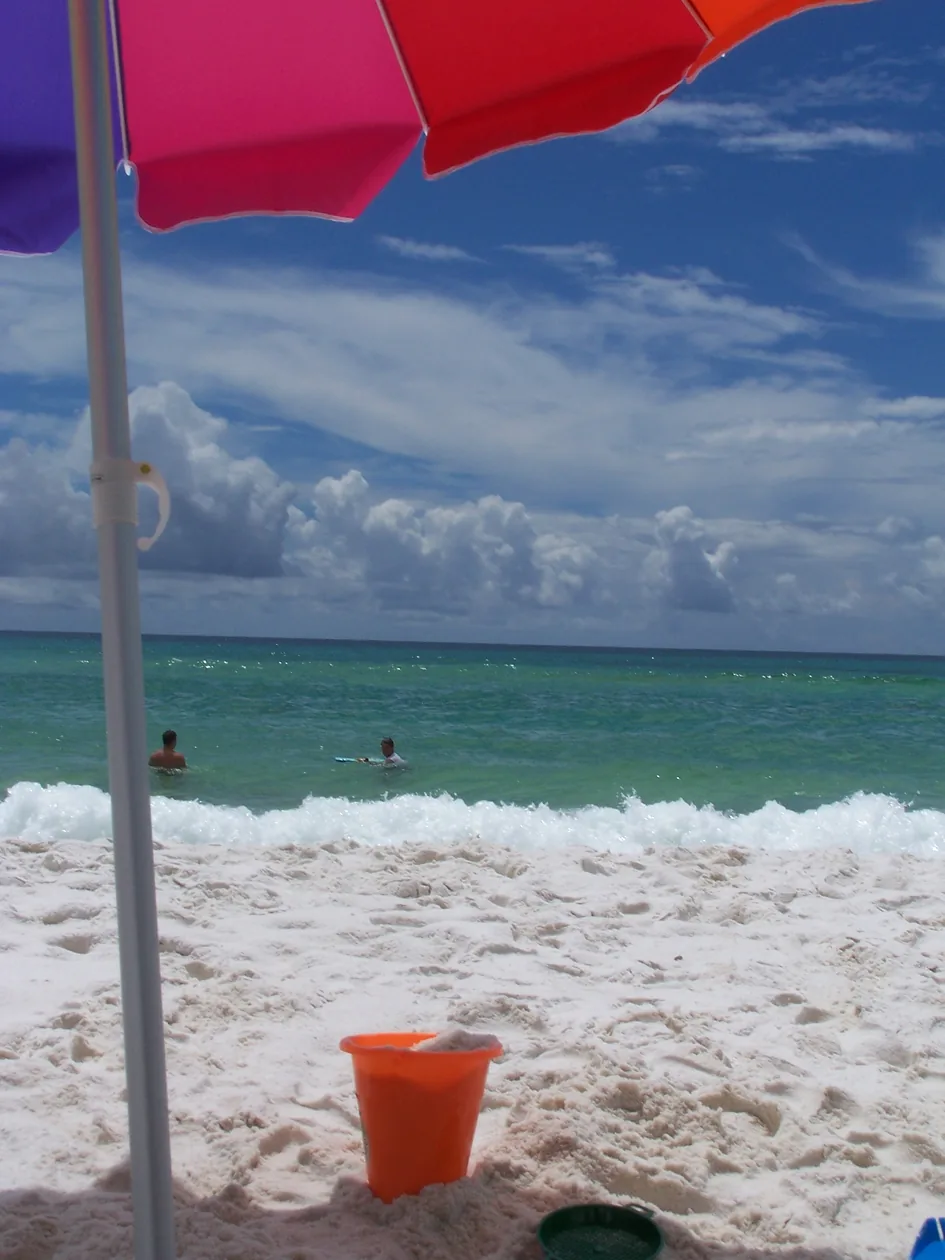 Emerald water and white sand on a Destin beach with a warning flag flying