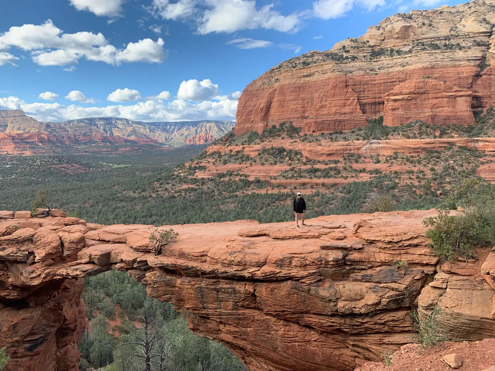 A hiker standing on the Devils Bridge rock arch in Sedona