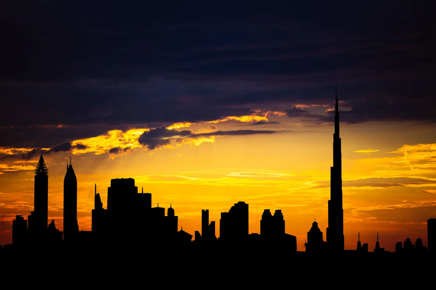 The Dubai skyline silhouetted against an orange sunset