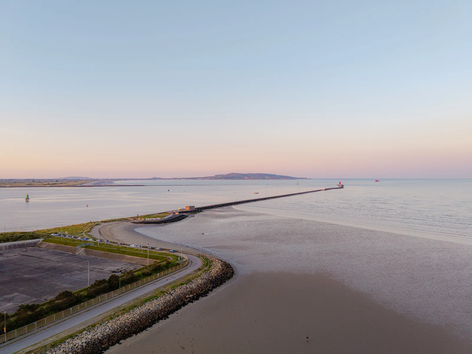 Dublin Bay at sunset with a long pier reaching into calm water