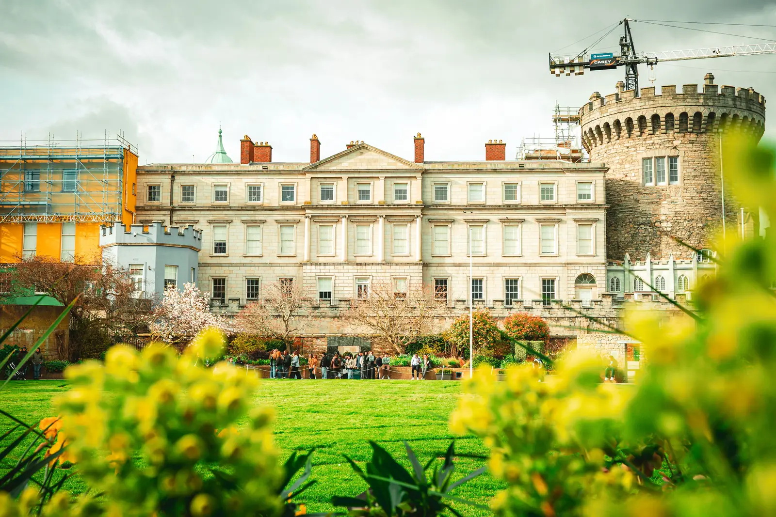 Dublin Castle behind green lawns and yellow spring flowers