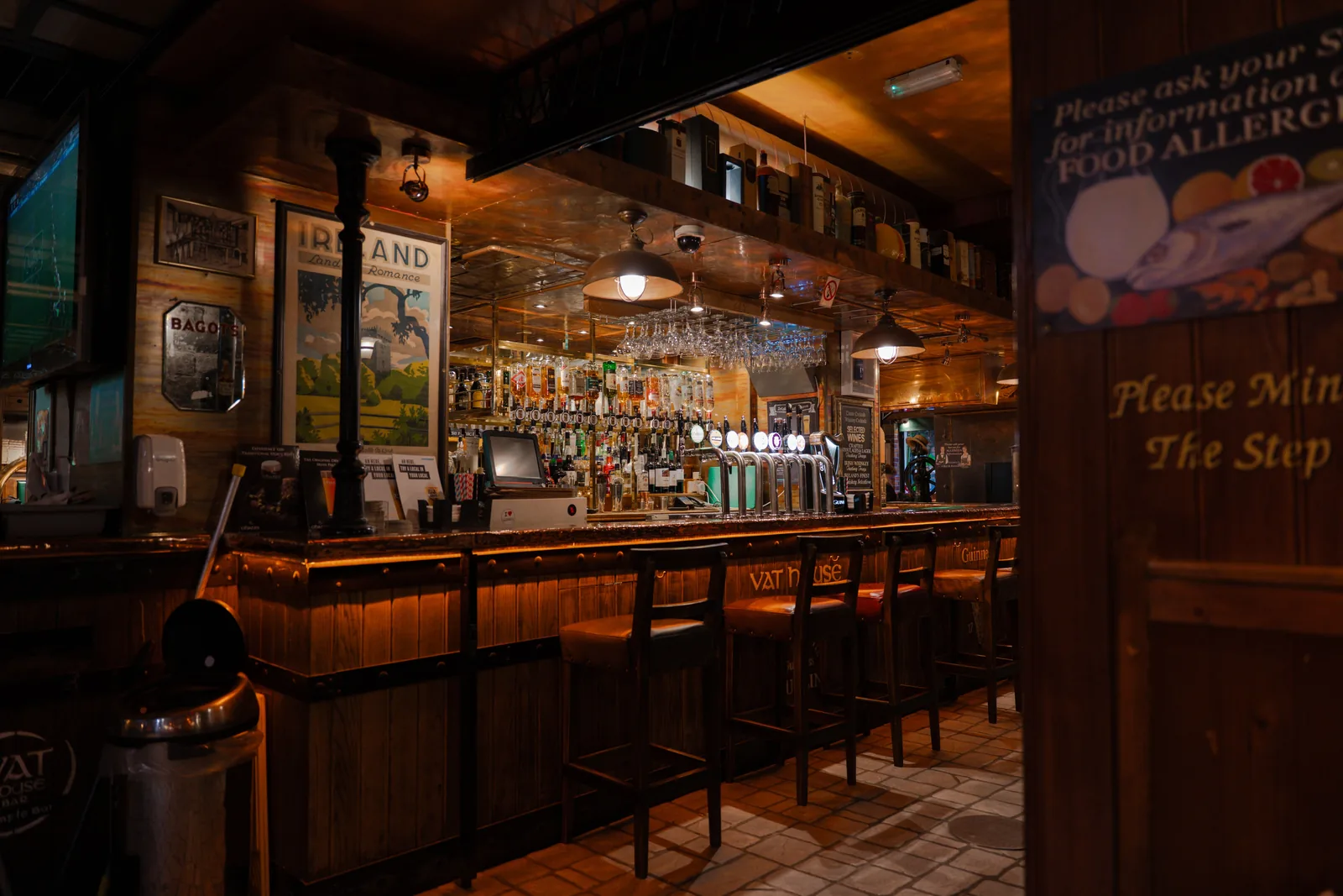 The warm wooden bar of a traditional Irish pub in the evening