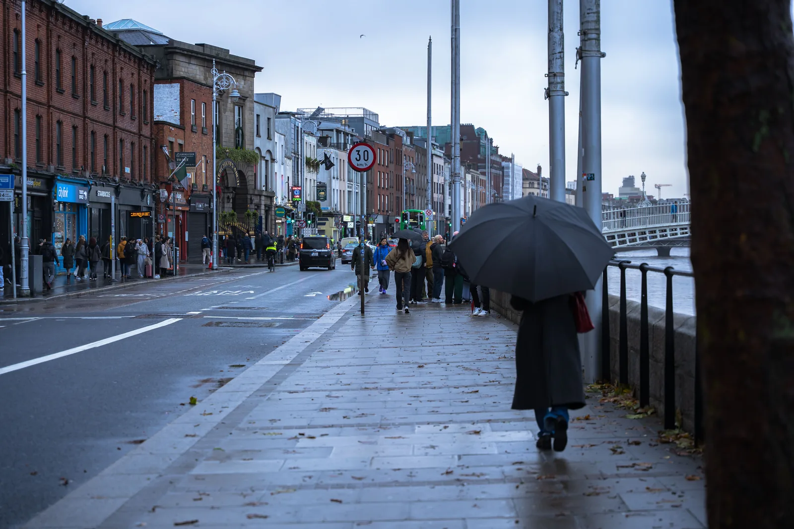 A person walking with an umbrella on a wet Dublin street