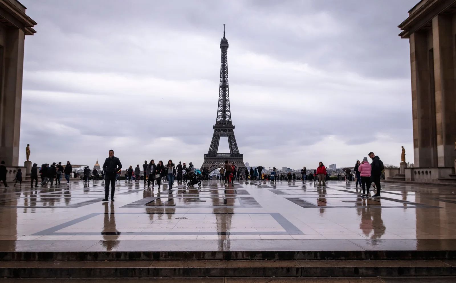Visitors looking across to the Eiffel Tower from a wet stone terrace