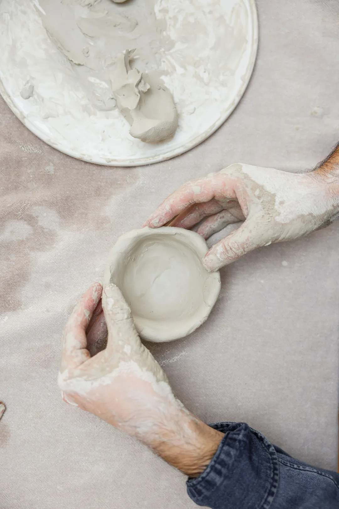 A potter shaping a clay bowl by hand in a workshop