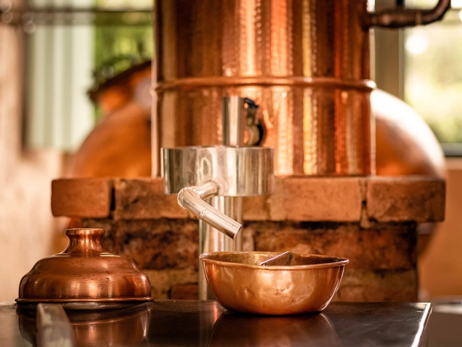Copper distilling equipment and tasting cups inside a distillery