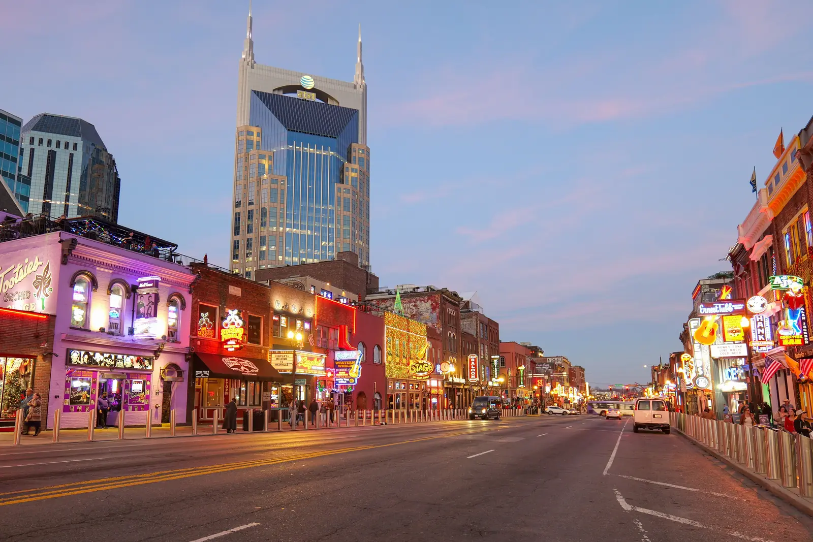 Neon signs glowing along Broadway in downtown Nashville at dusk