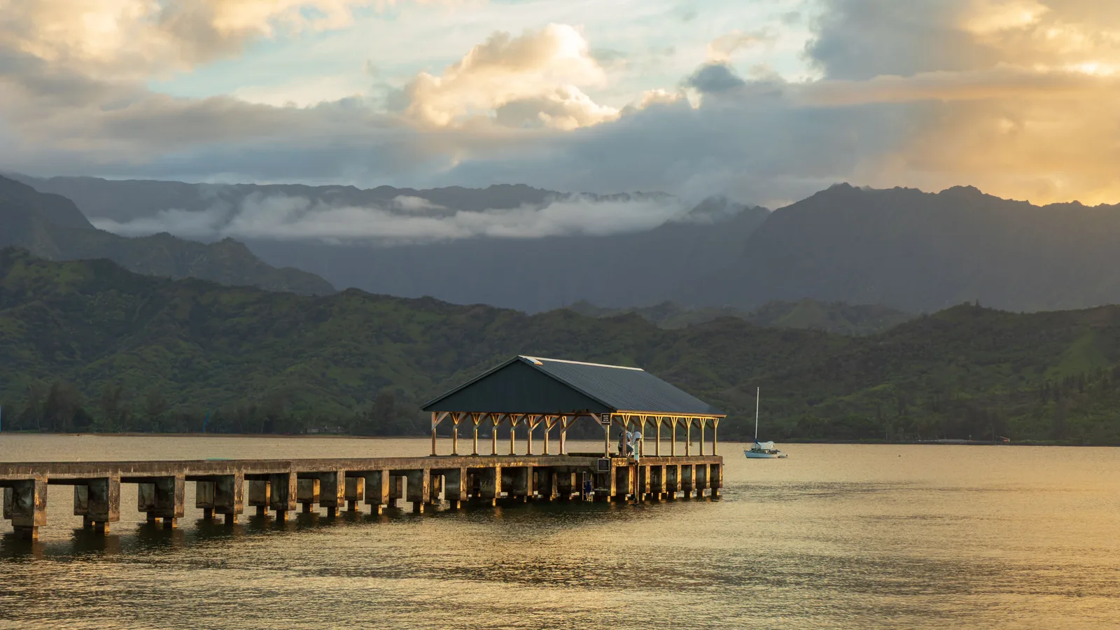 Hanalei Pier reaching into the bay at sunset with mountains behind it, Kauai