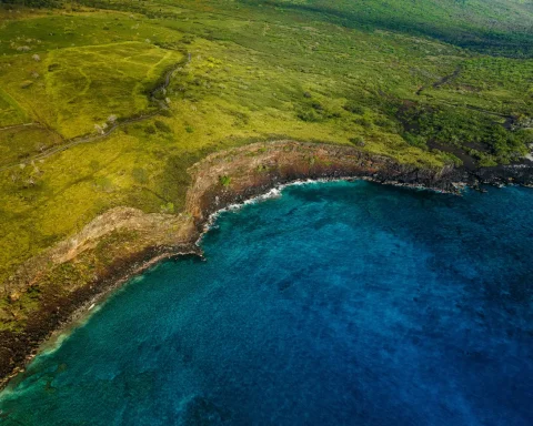 Green cliffs dropping into deep blue water along the Kohala Coast in Hawaii