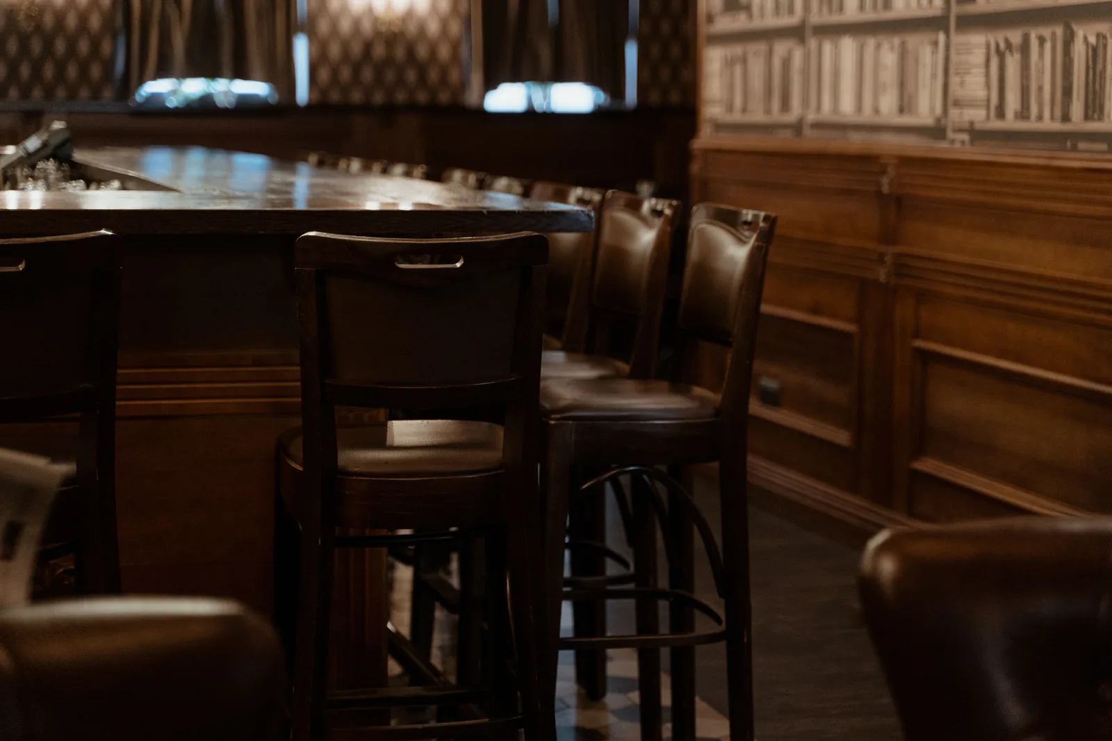 A dark wooden bar with panelled walls and old bar stools