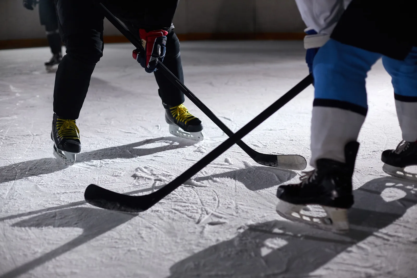 A close view of players' skates and sticks battling for the puck on the ice
