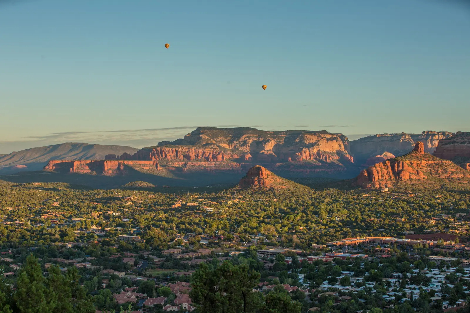 Hot air balloons over a red rock valley at first light