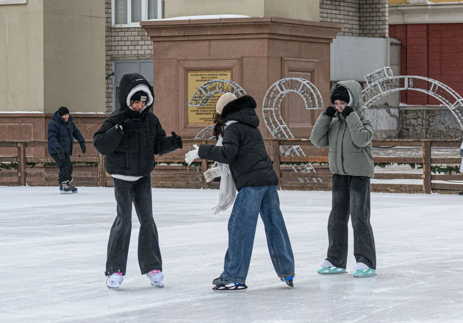 Friends skating together on an outdoor ice rink in winter