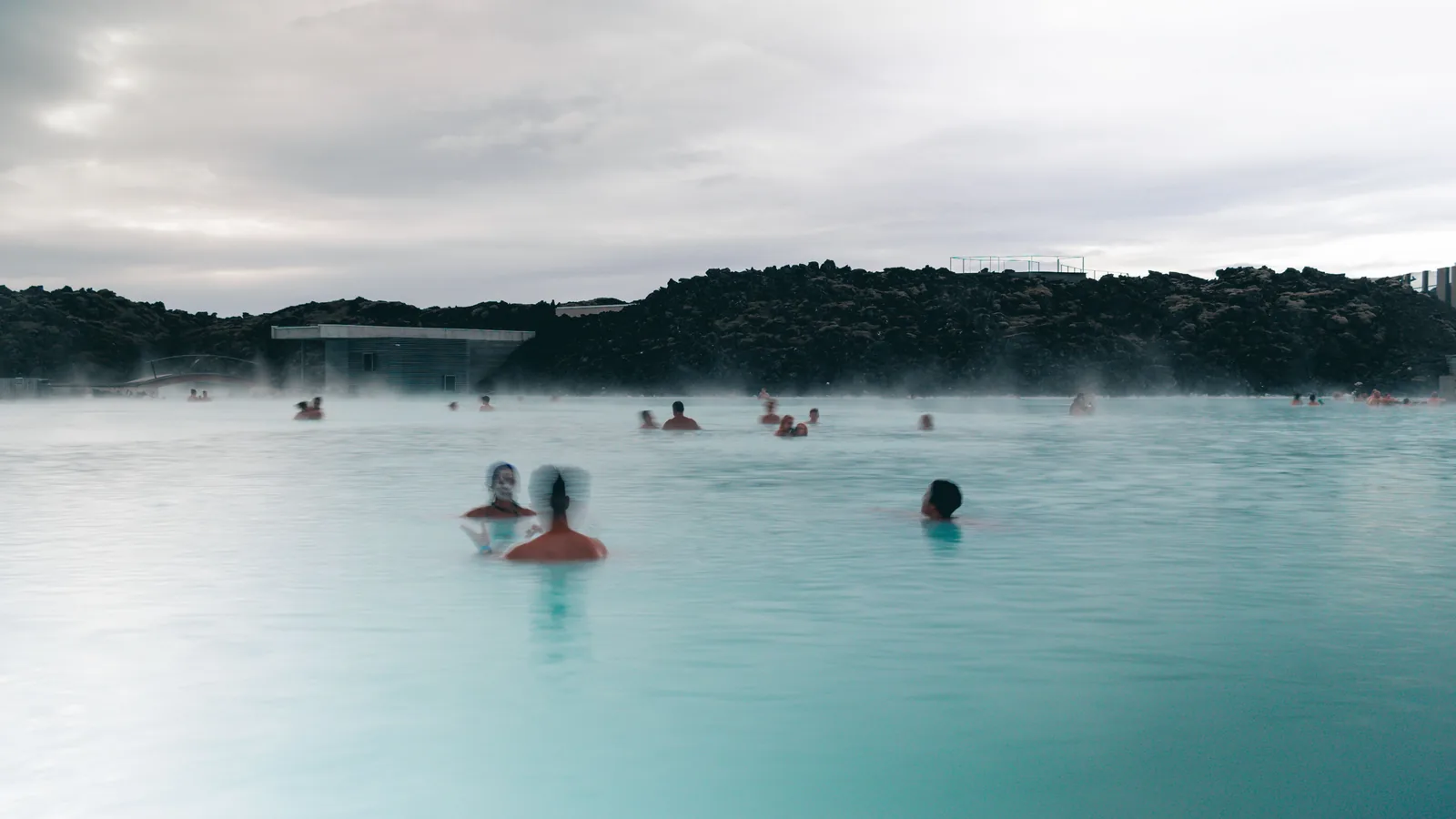 Bathers in the milky blue geothermal water of the Blue Lagoon with steam rising