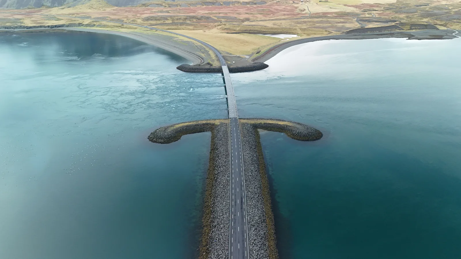 A narrow causeway road crossing water in Iceland seen from above