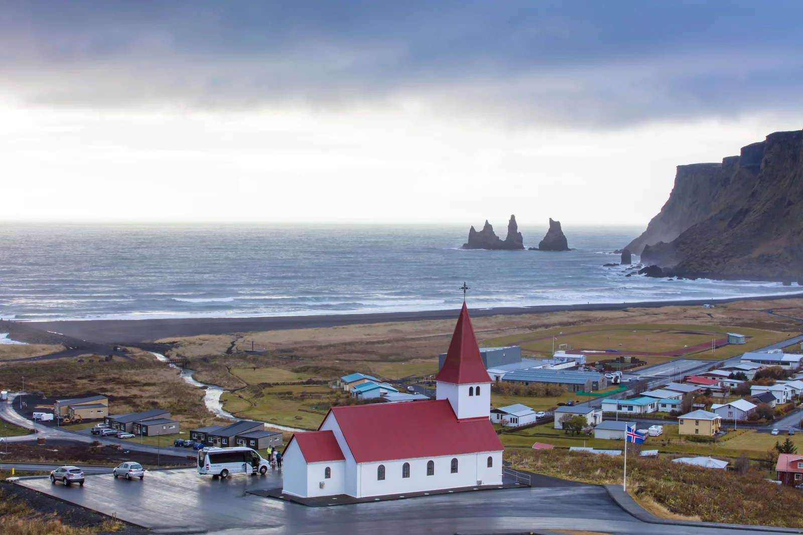 The red roofed church above the village of Vik with the black coastline beyond