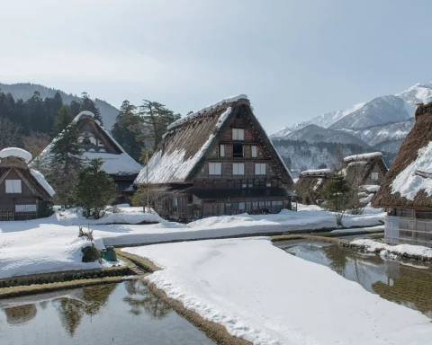 Thatched farmhouses at Shirakawa Go under snow with mountains behind