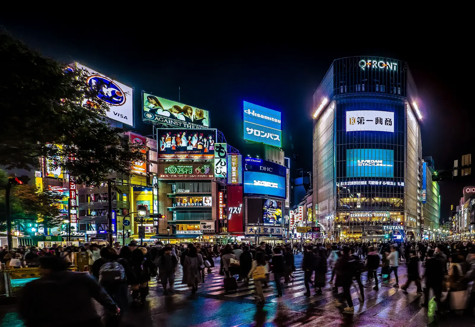 Crowds crossing Shibuya Scramble Crossing under neon screens at night