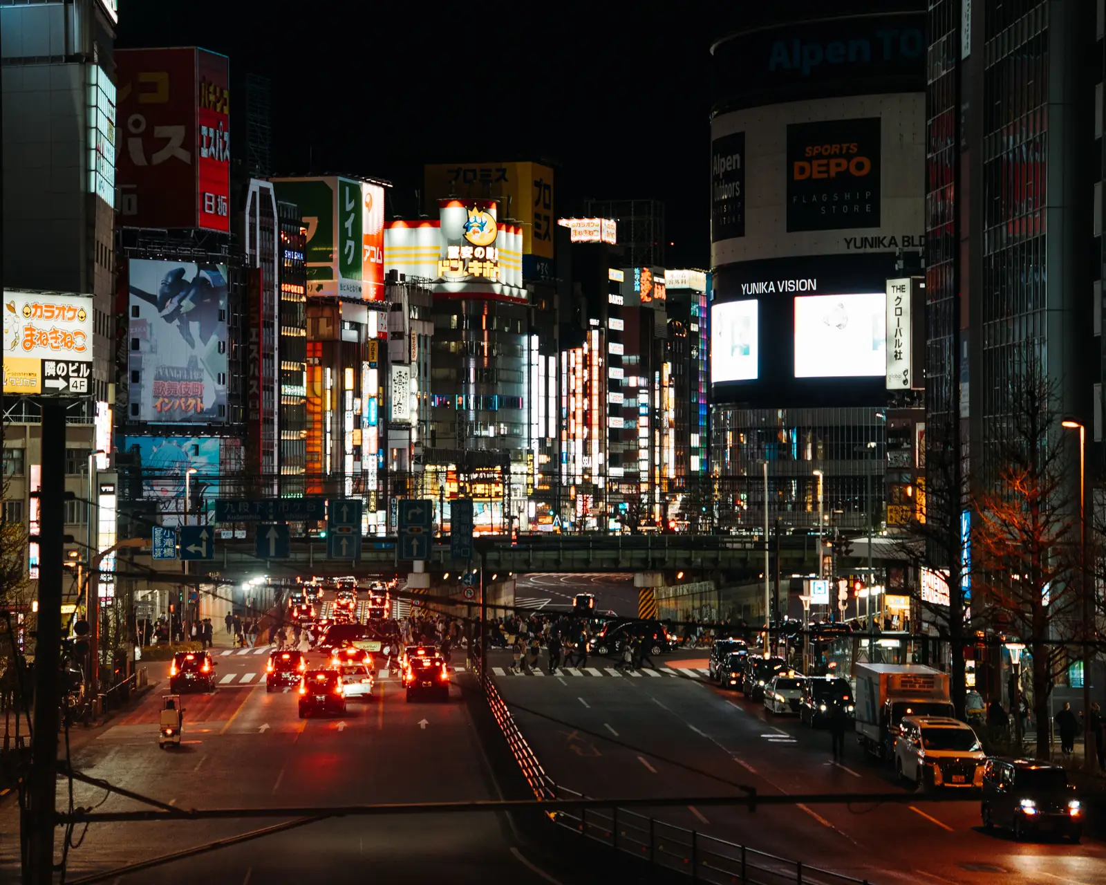 Neon signs above a busy street in Shinjuku, Tokyo at night