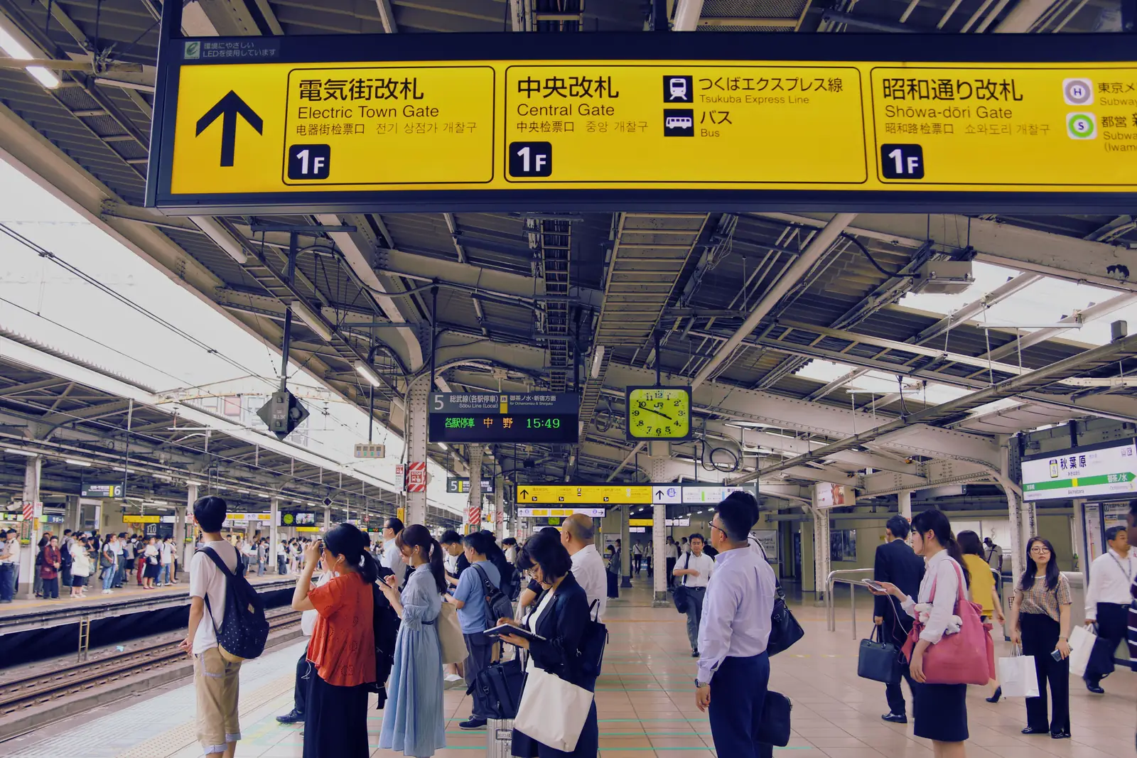 Commuters waiting on a platform below the signs at a Tokyo train station