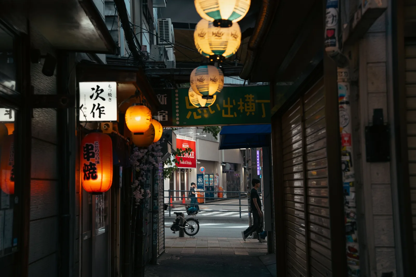 A narrow Tokyo alley lined with paper lanterns and small bars at dusk