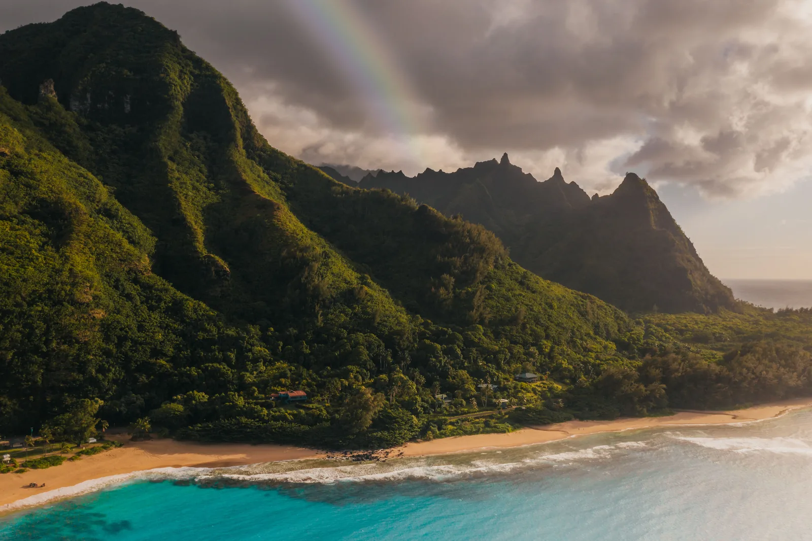 A rainbow over green cliffs above a turquoise bay on Kauai's north shore