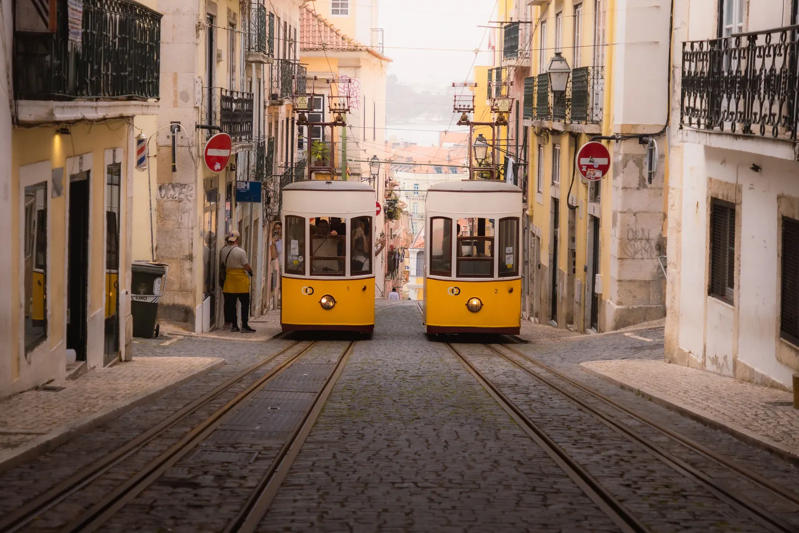 Two yellow trams passing on a narrow cobbled street in Lisbon, Portugal