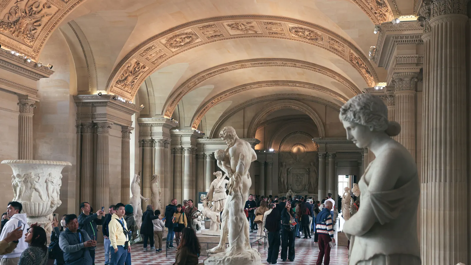 Visitors among the classical statues in a sculpture hall at the Louvre