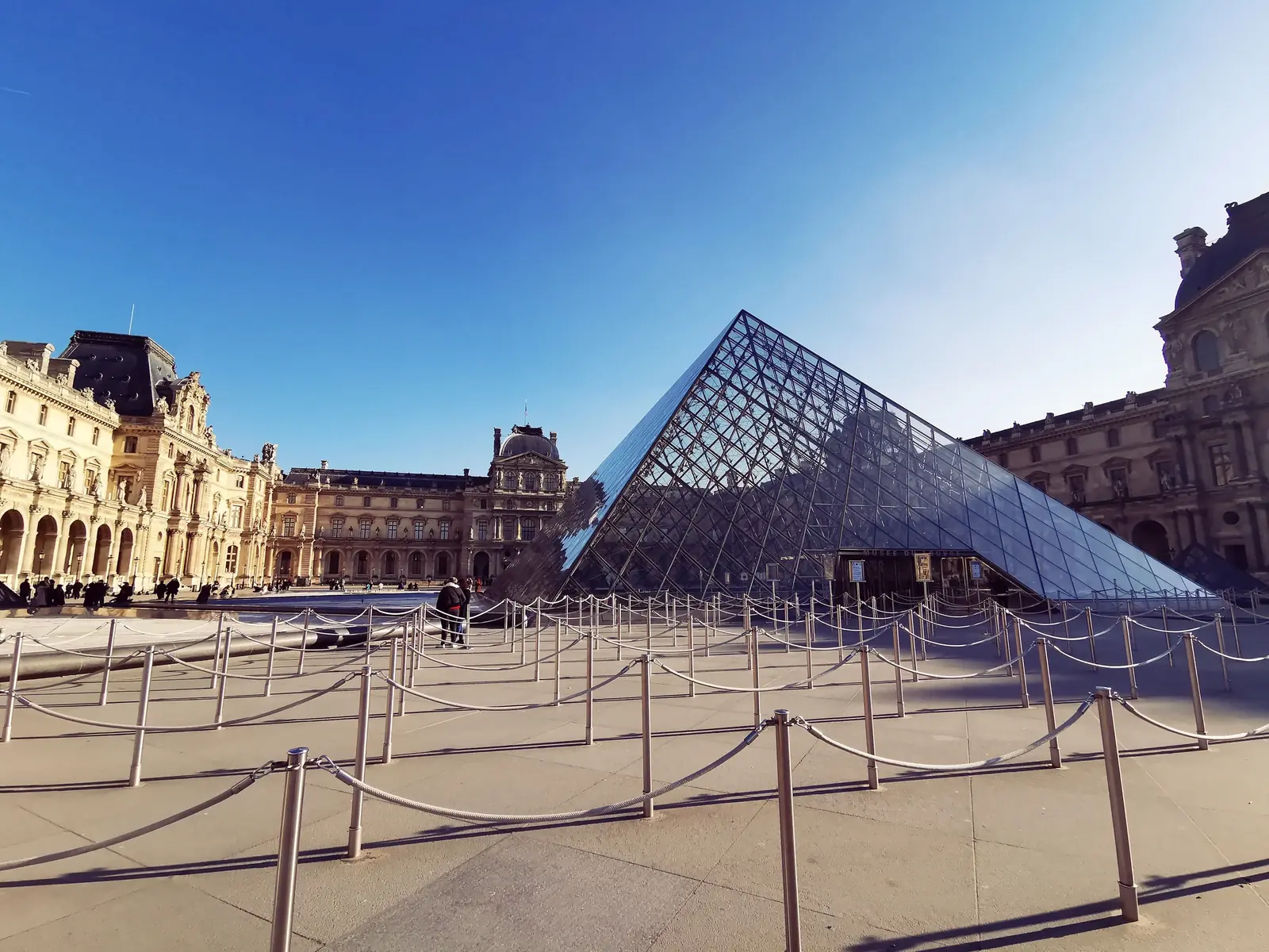 Empty queue barriers standing in front of the glass pyramid at the Louvre