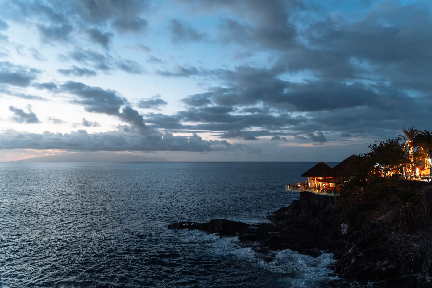 A seaside restaurant lit up above the water at dusk