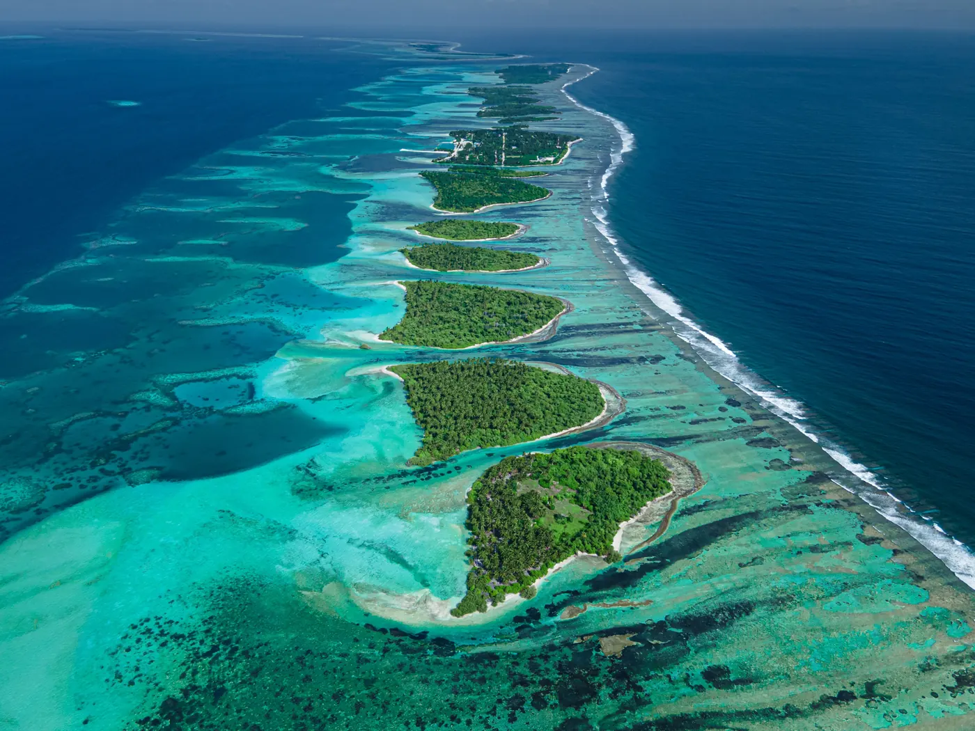 An aerial view of a long thin atoll island in the Maldives
