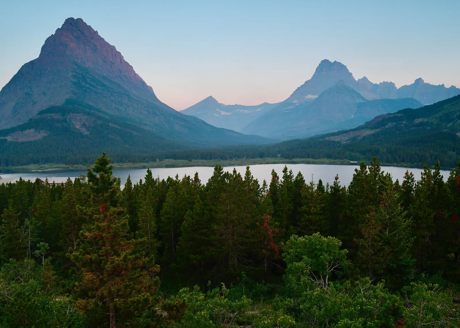 Mountains reflected in a still lake at dawn in the Many Glacier valley