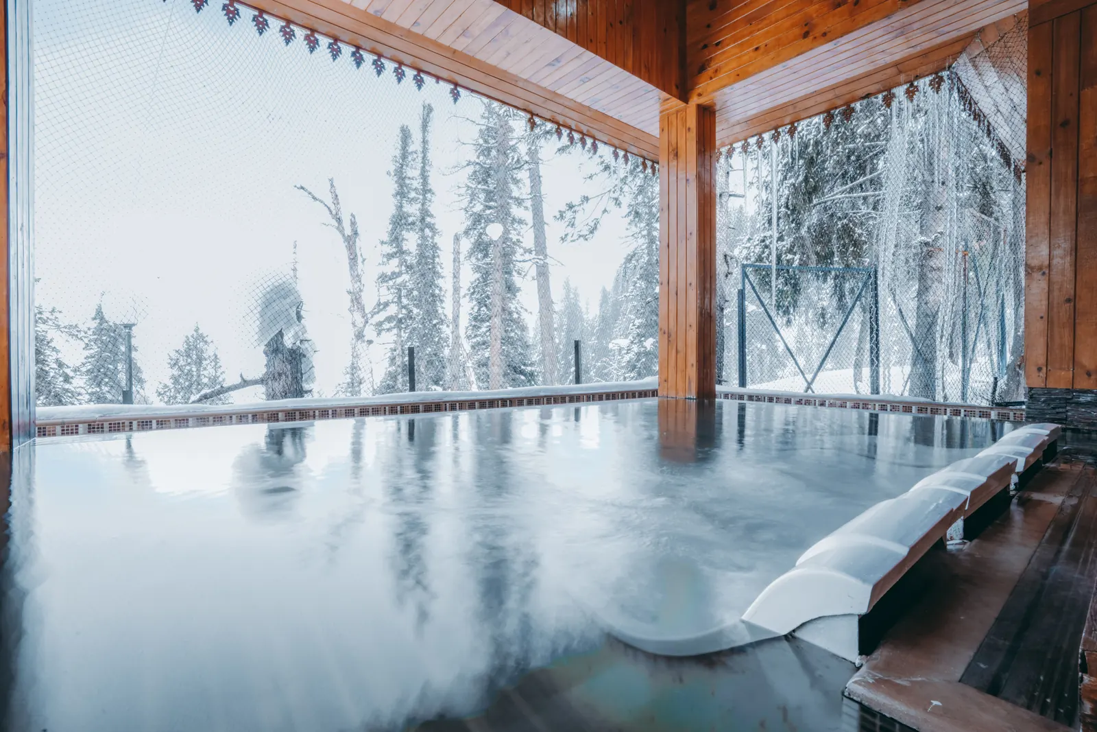 An outdoor thermal pool surrounded by snow covered trees