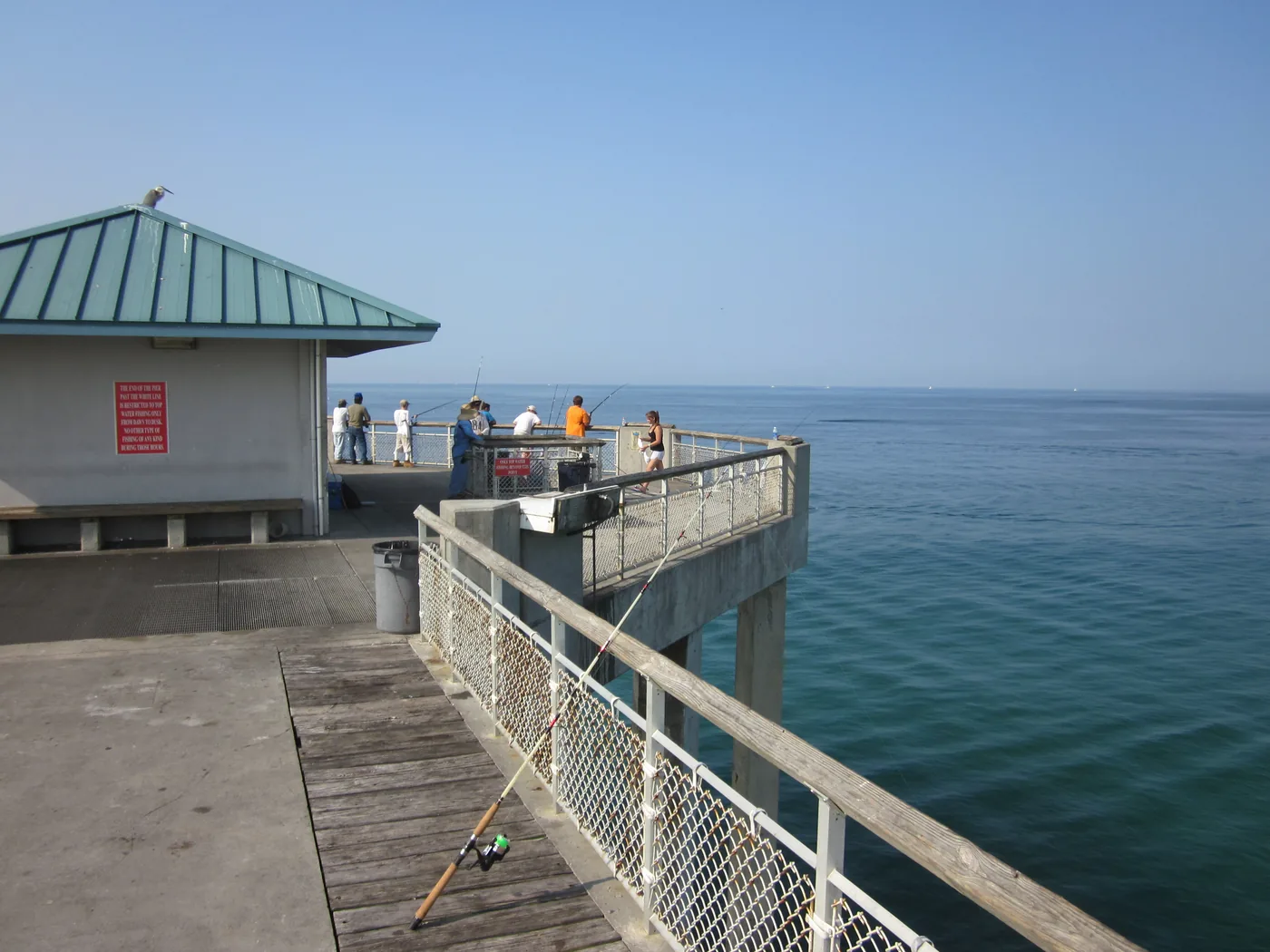 Anglers fishing from the deck of the Okaloosa Island Pier over green water