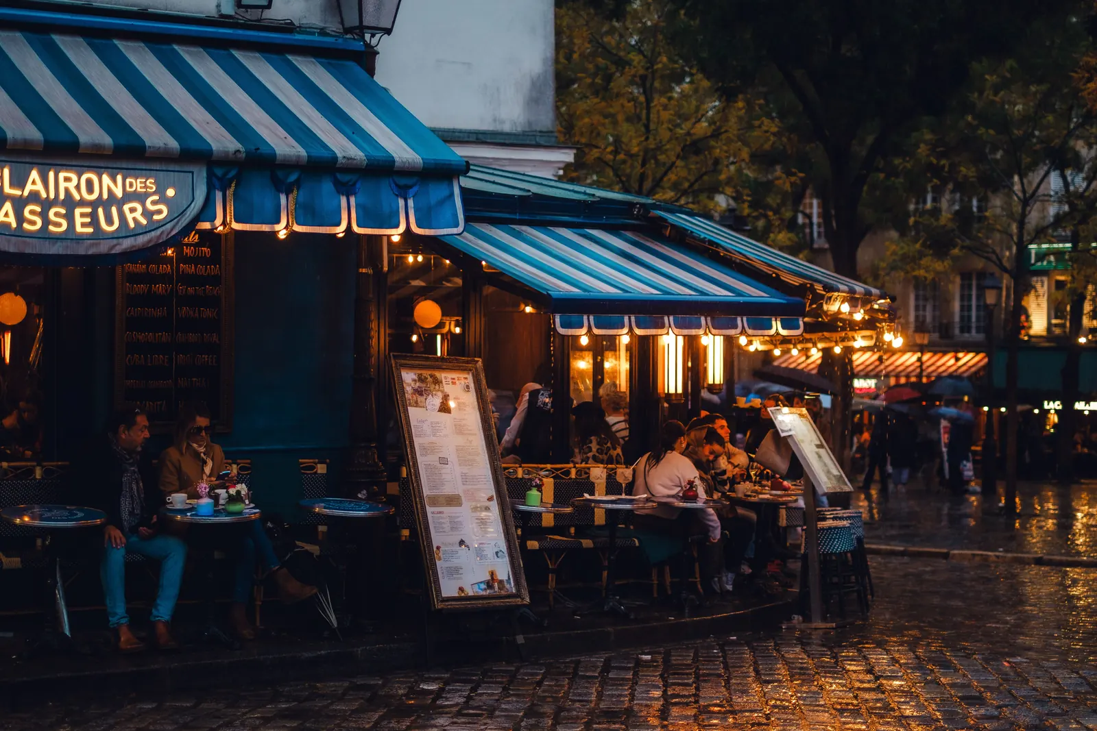A Paris cafe terrace lit up on a wet evening