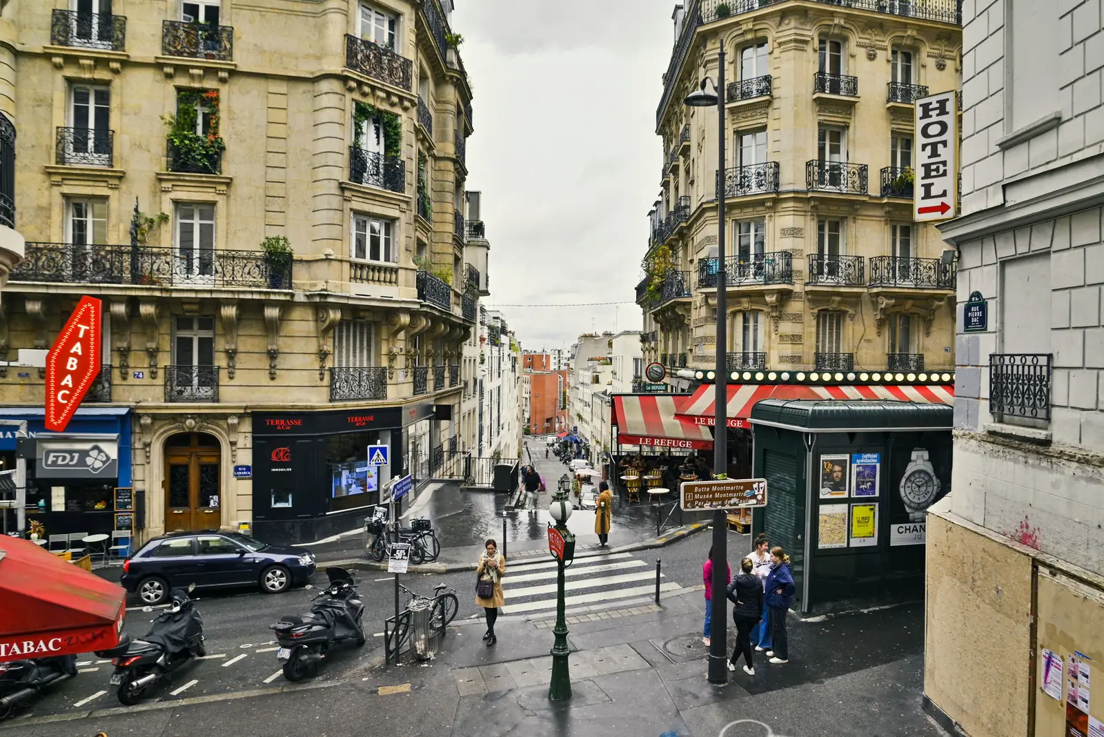 A hotel sign above a busy street corner in Montmartre, Paris