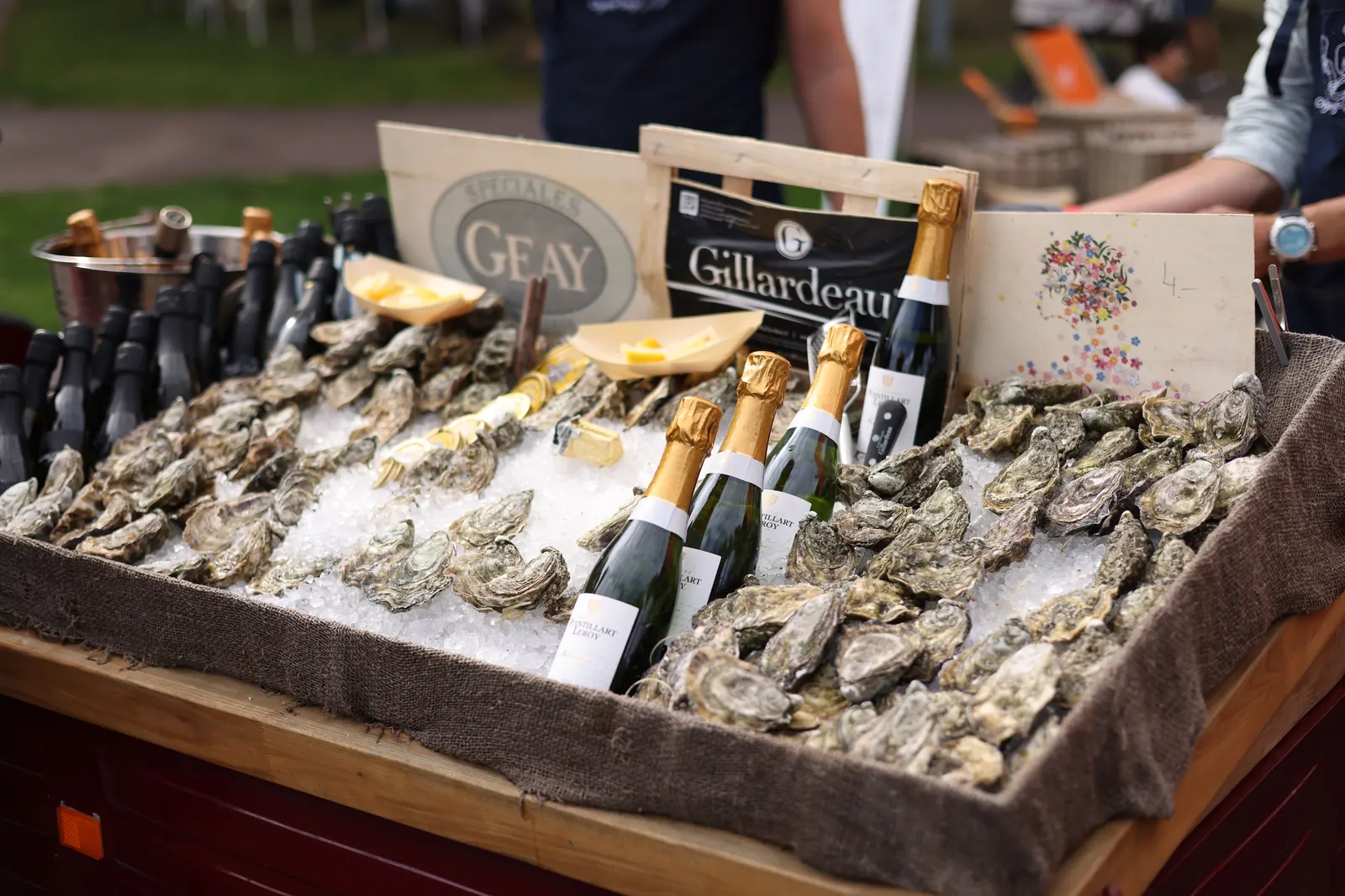 French oysters on ice beside champagne bottles at a seafood stall