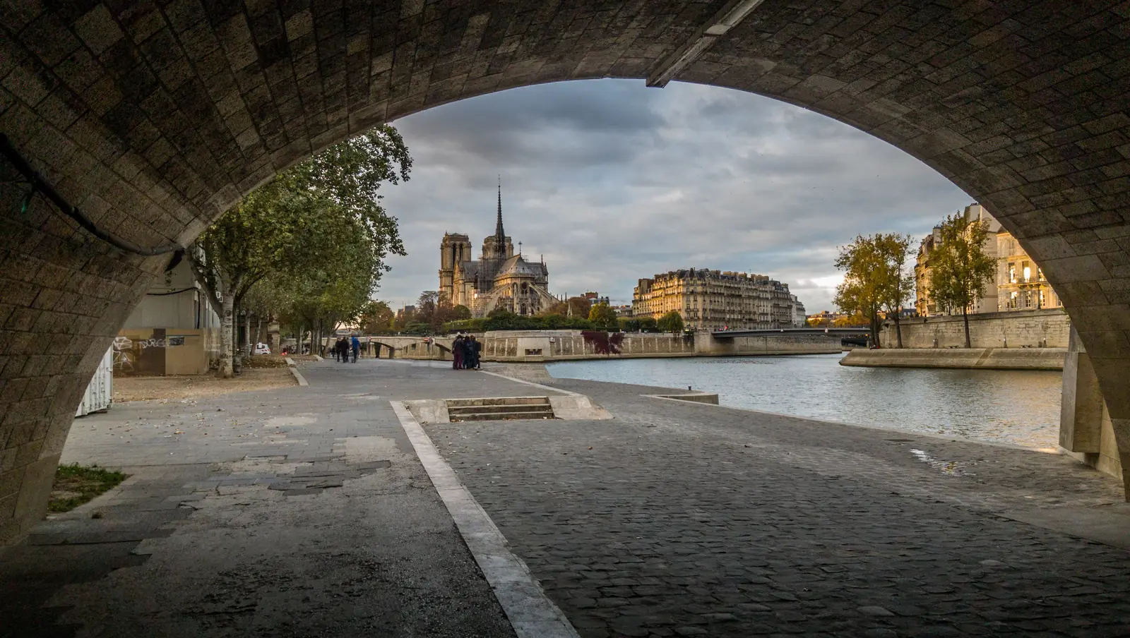 People walking and sitting along the riverbank in Paris