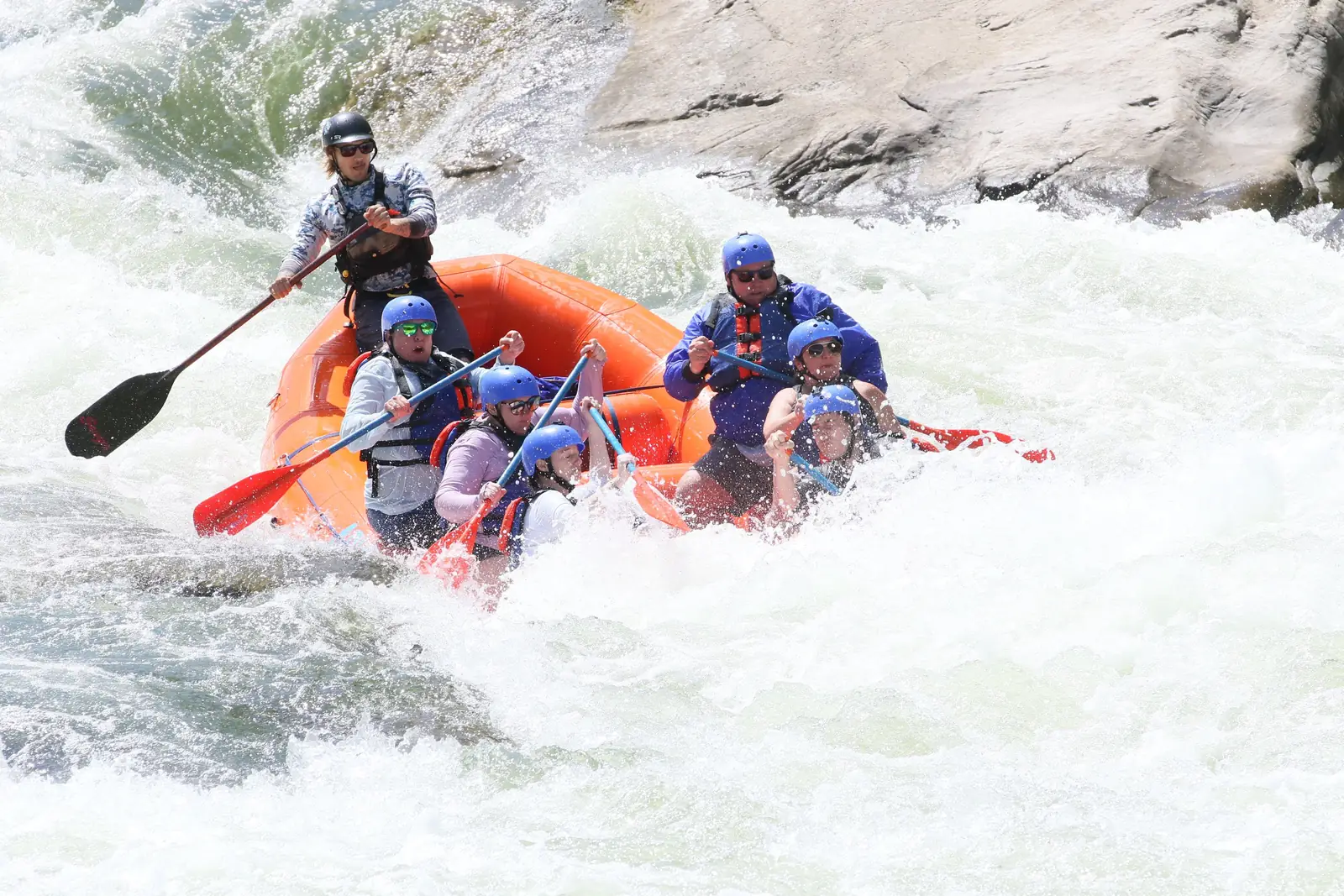A raft of paddlers dropping through whitewater rapids