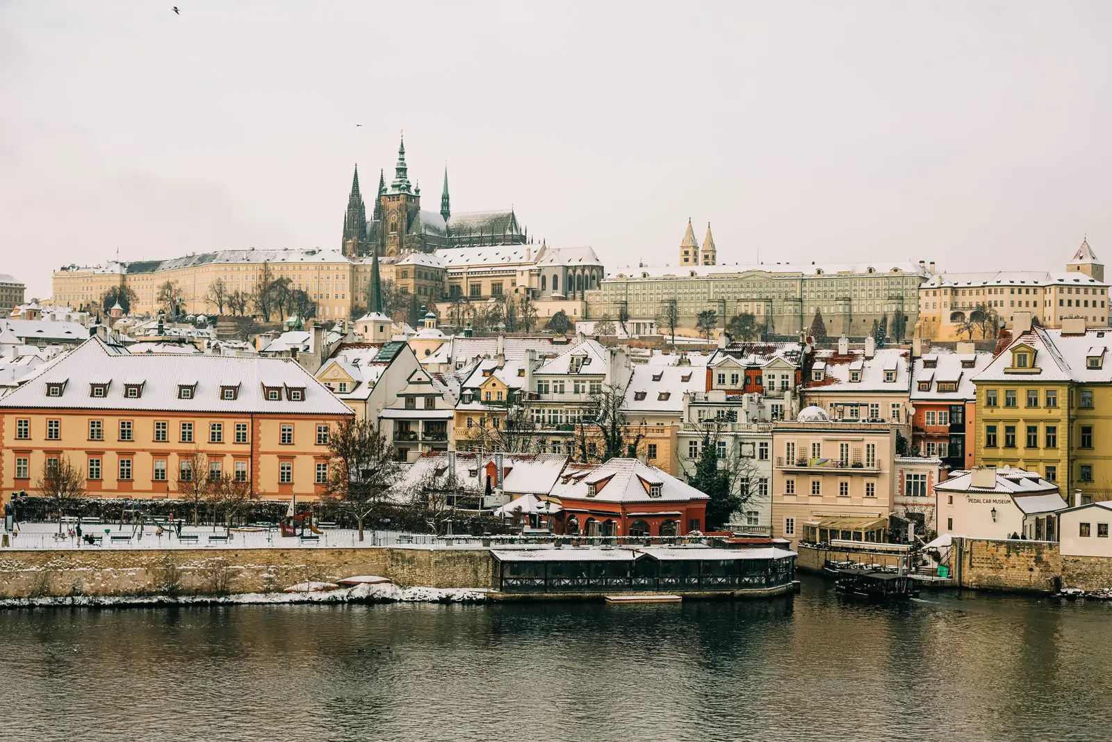 Snow on the rooftops of Prague with the castle above the river