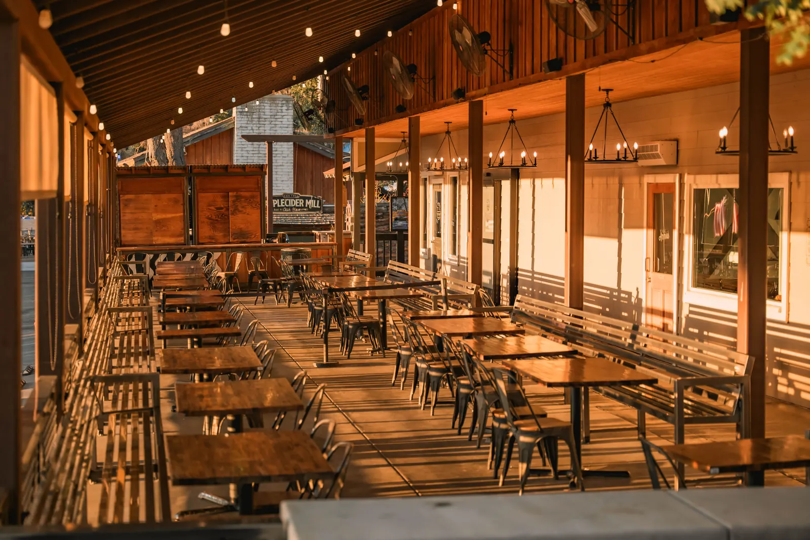 A long covered porch strung with lights and lined with picnic tables