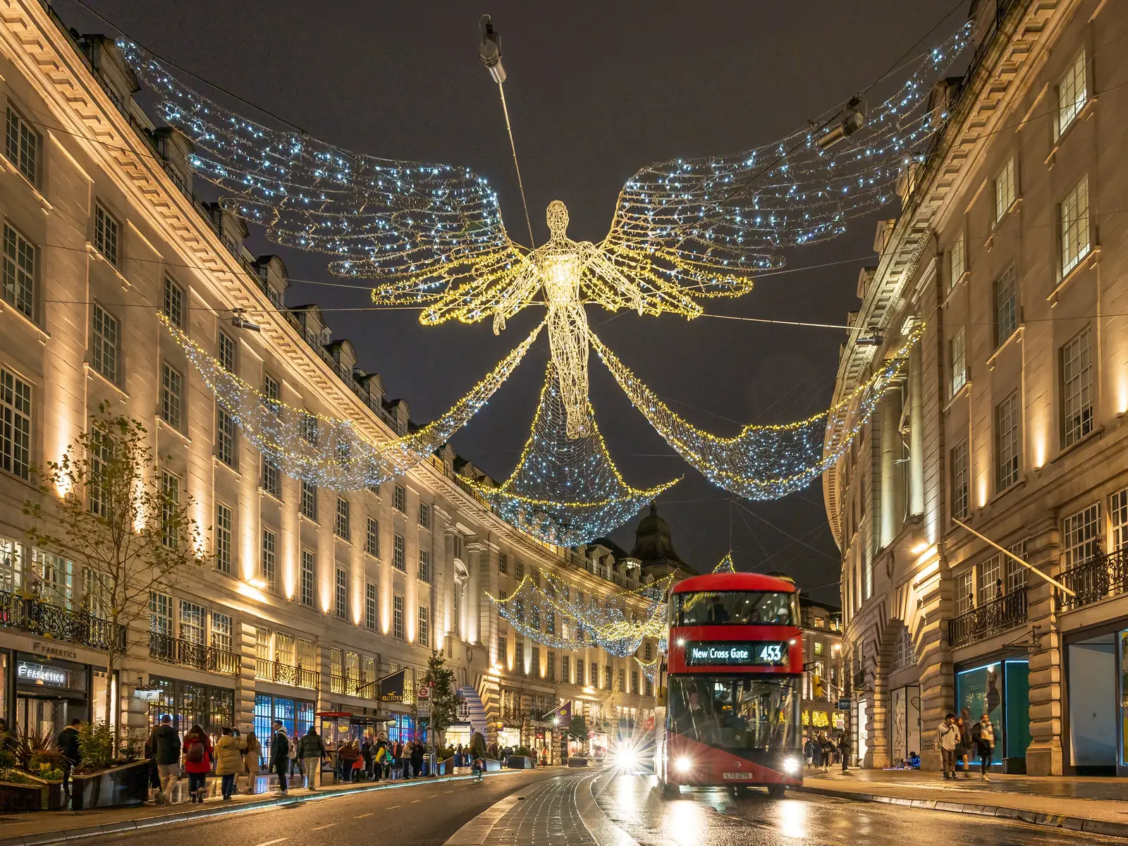 A red double decker bus passing under the angel lights on Regent Street