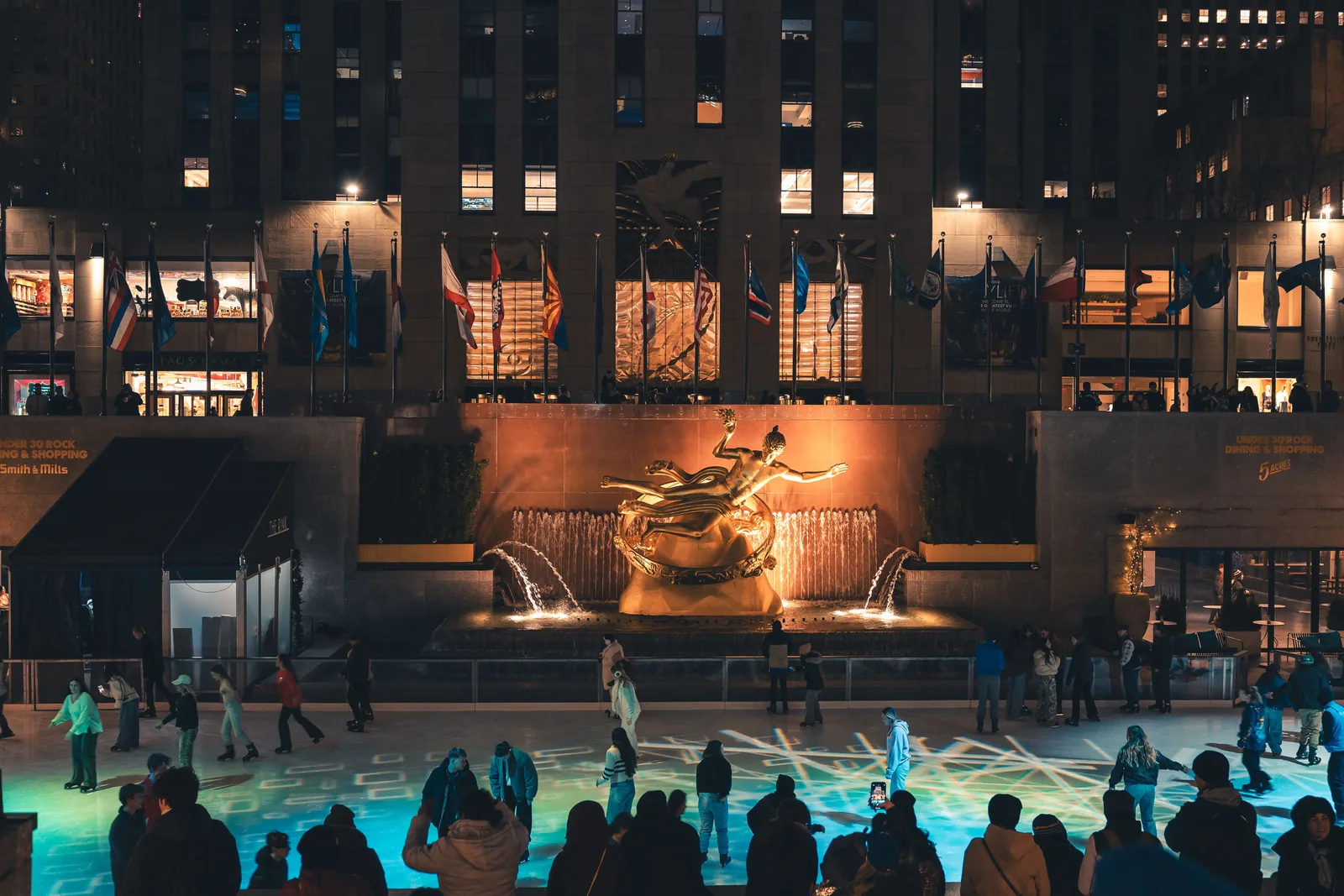 Skaters on the rink at Rockefeller Center below the lit Prometheus statue