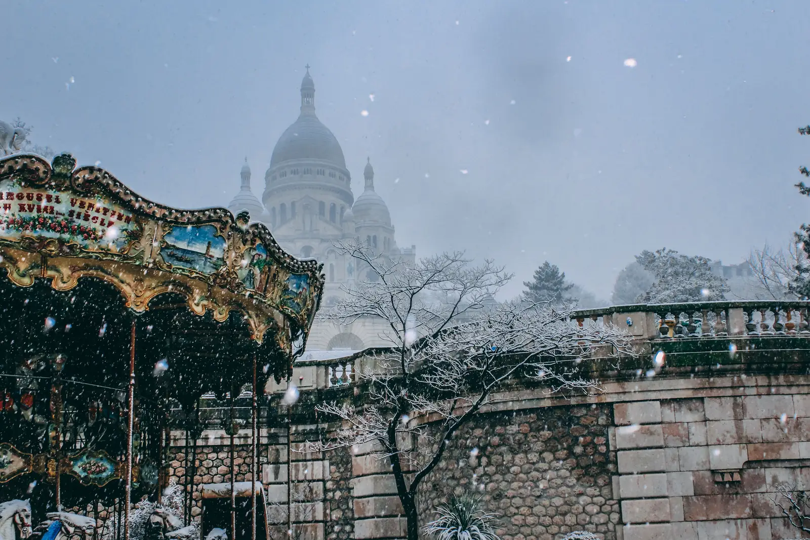 Snow falling over the Sacre Coeur basilica and the carousel below it in Montmartre