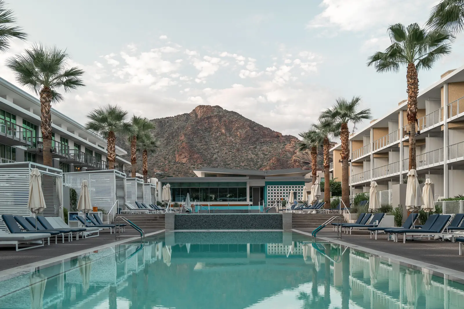 A resort swimming pool ringed by palm trees below the desert mountains in Scottsdale