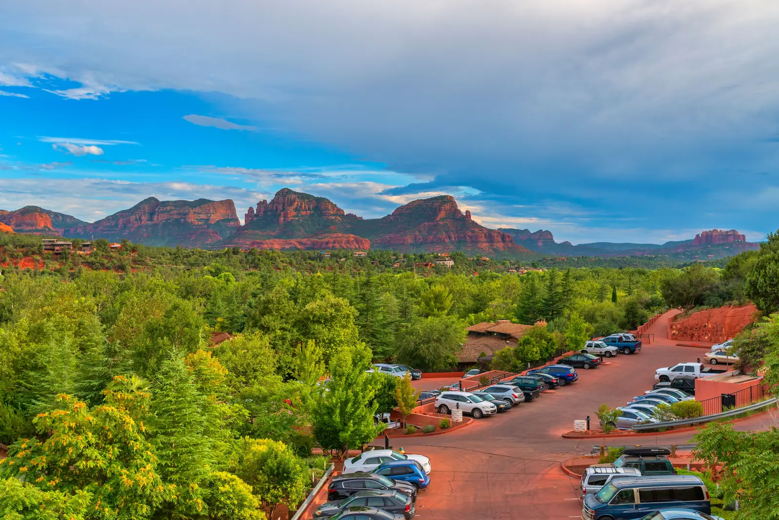 Cars parked at a trailhead lot below the red rocks in Sedona