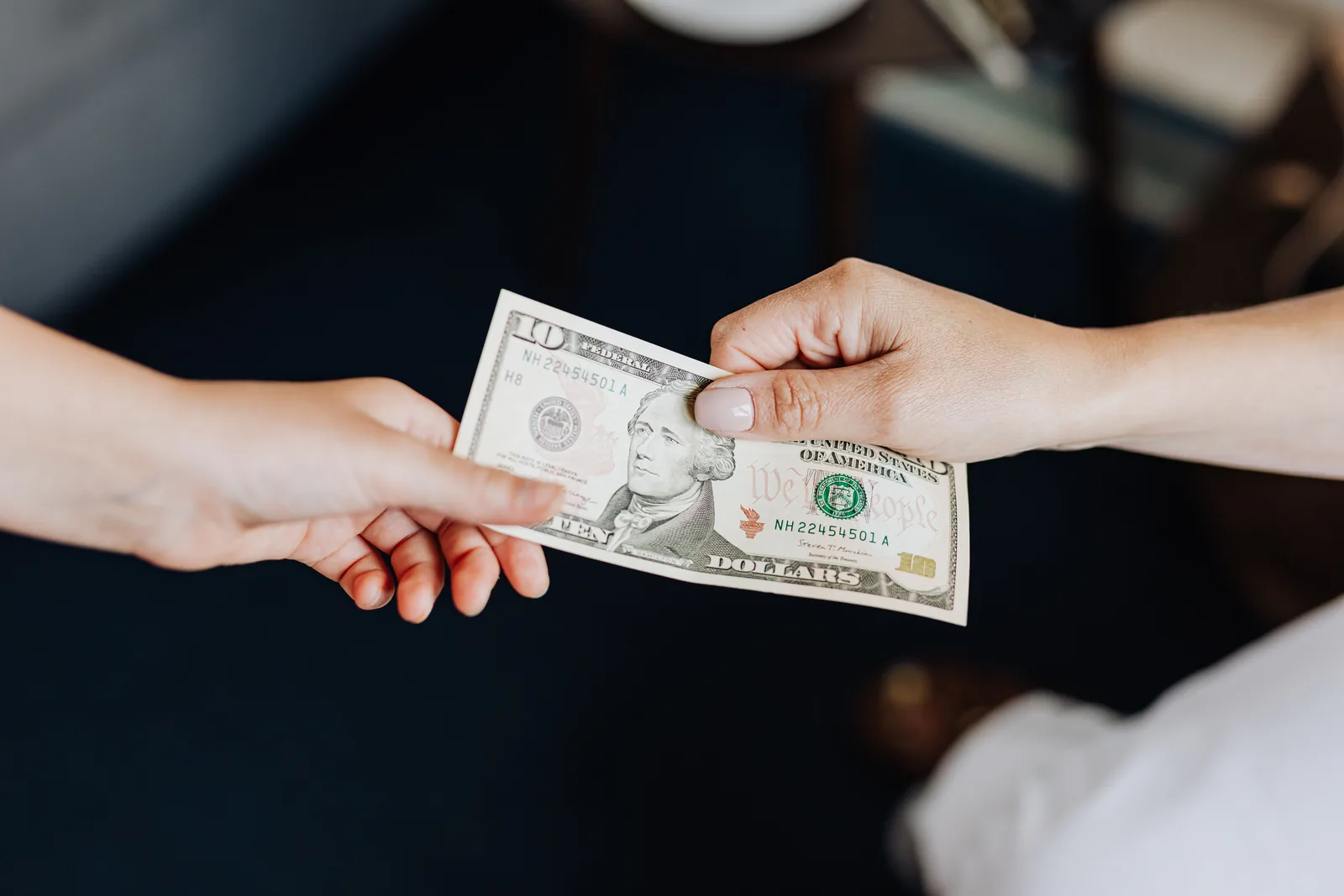 One person handing a folded bank note to another